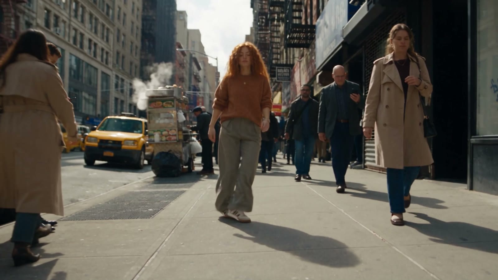 A woman with red hair dancing down a busy New York street