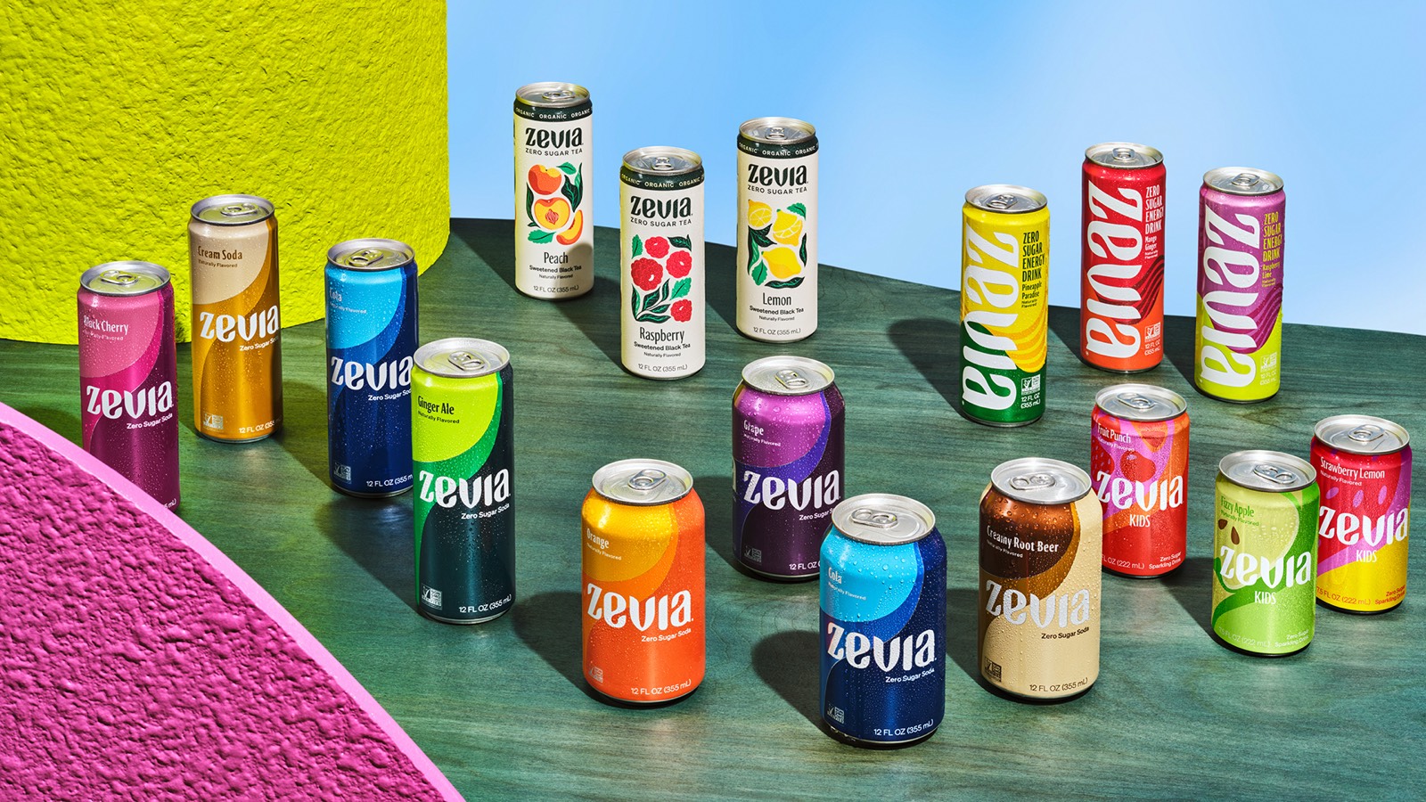 Zevia soda cans arranged on a green stage against a blue sky