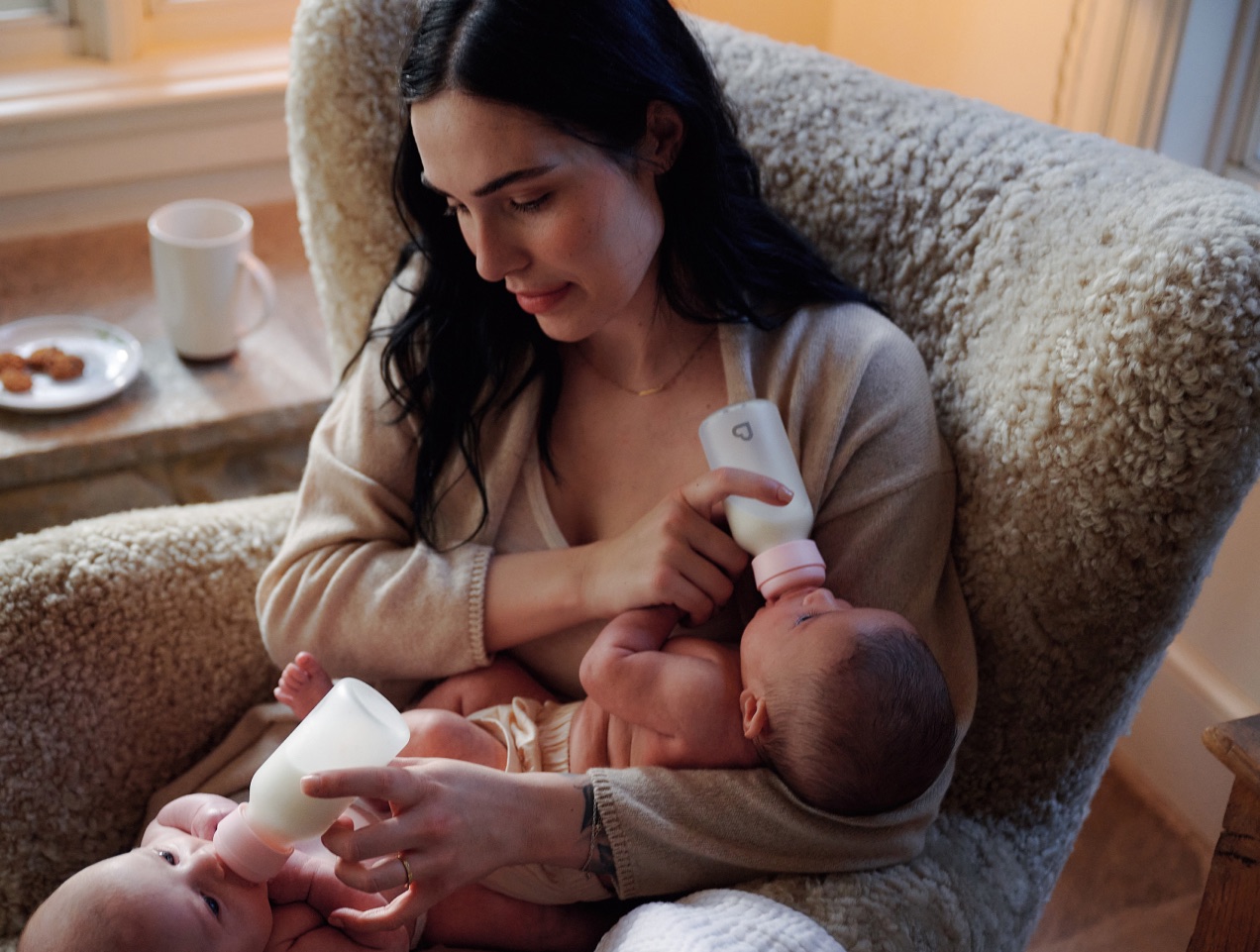 A mother in an armchair feeding her baby a bottle