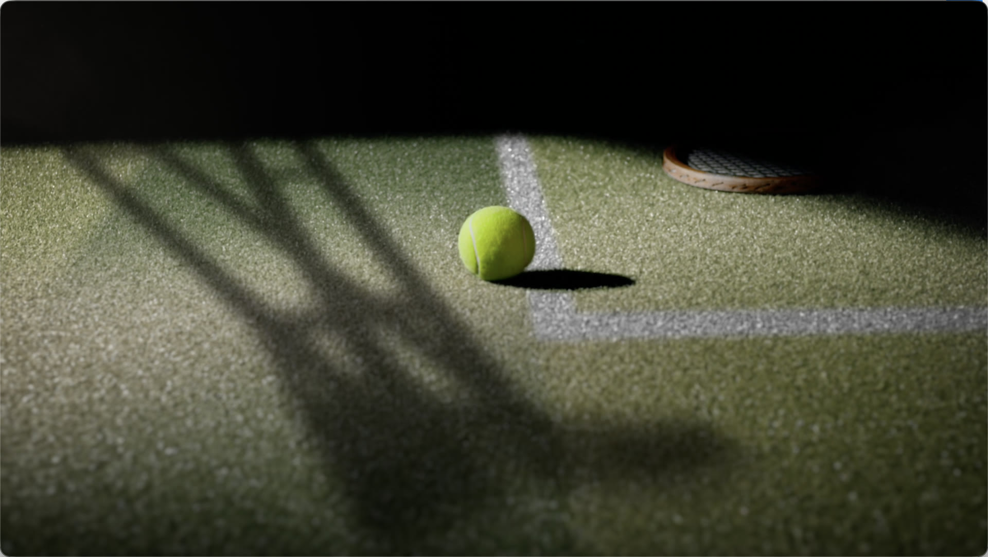 A tennis ball in a pool of light on a dark court