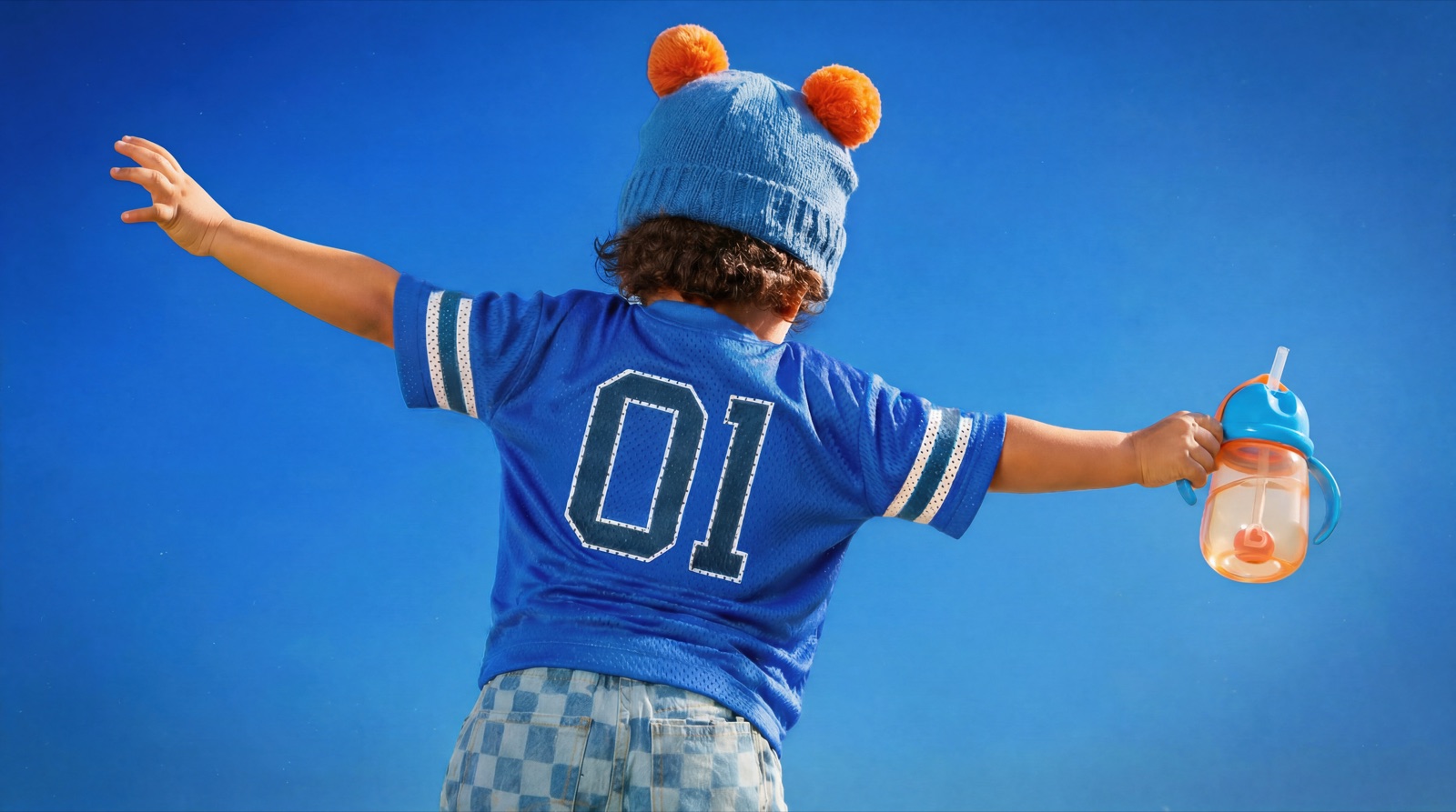 A child in a blue jersey holding a Munchkin cup
