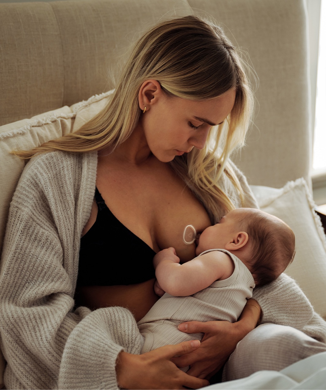 A mother breastfeeding her baby on a sofa
