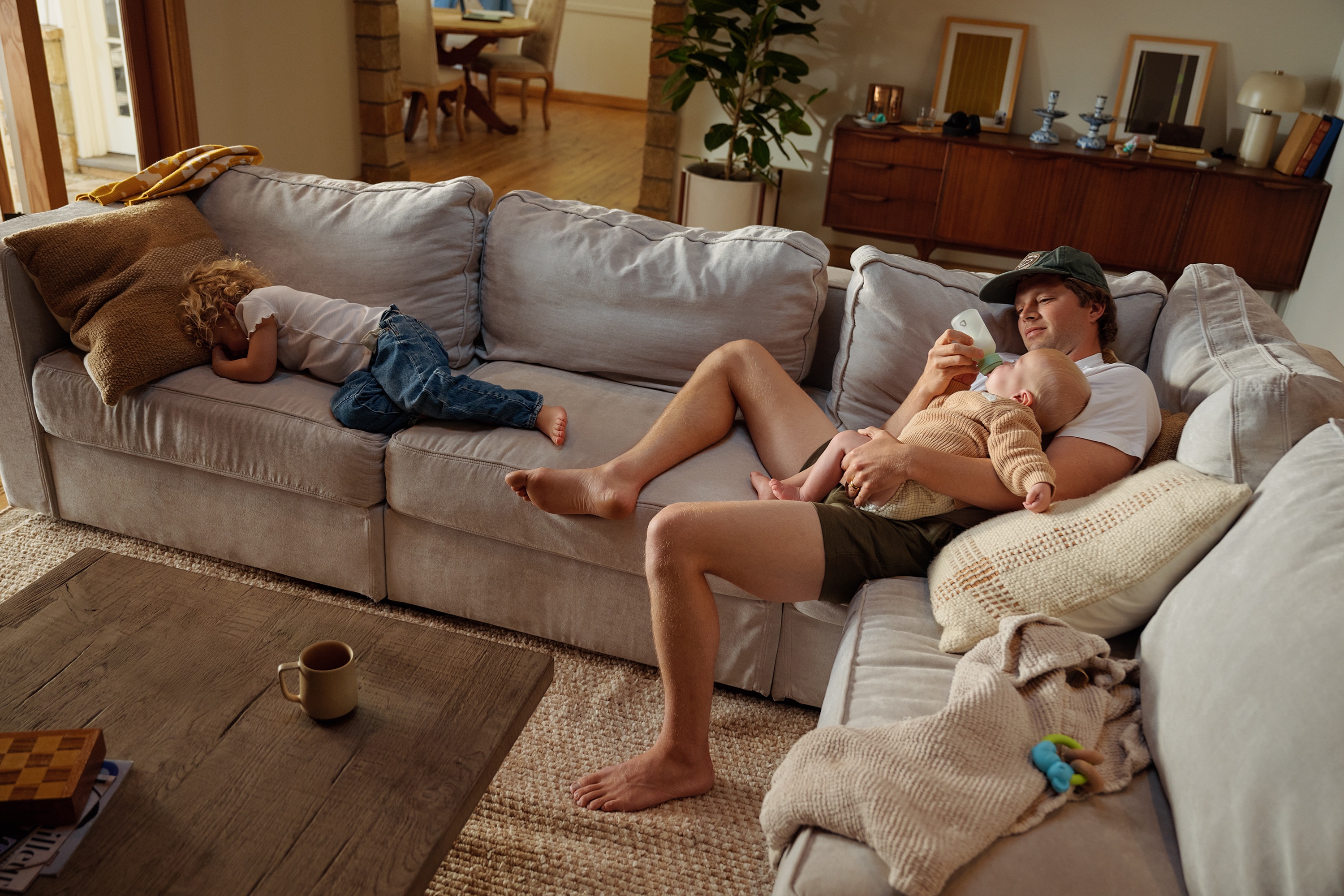 A father bottle-feeding his baby on a sofa