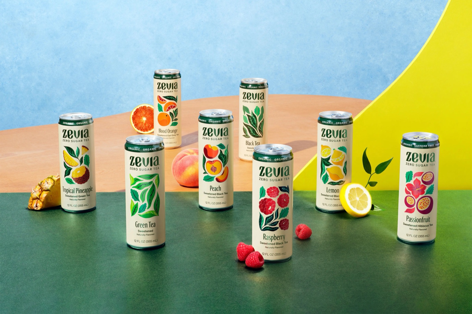 Zevia Tea cans arranged with fruit and botanicals against a blue and yellow backdrop
