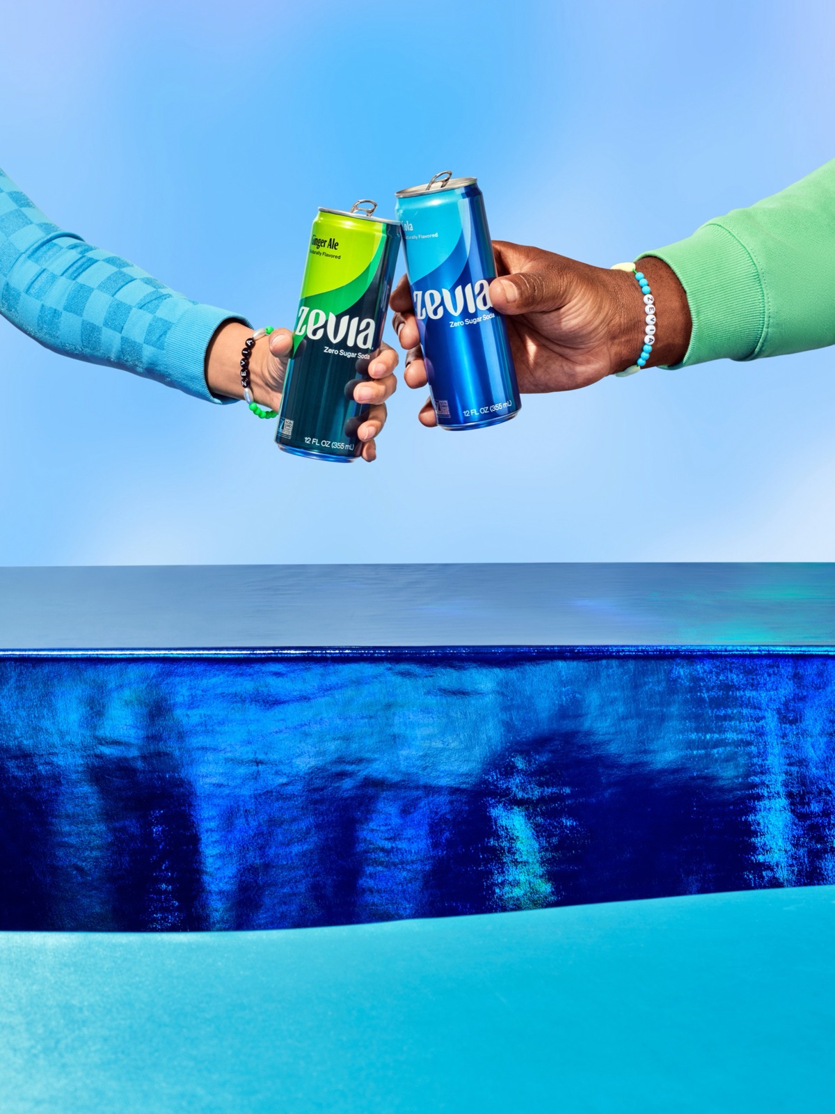 Two hands clinking Zevia cans against a blue sky